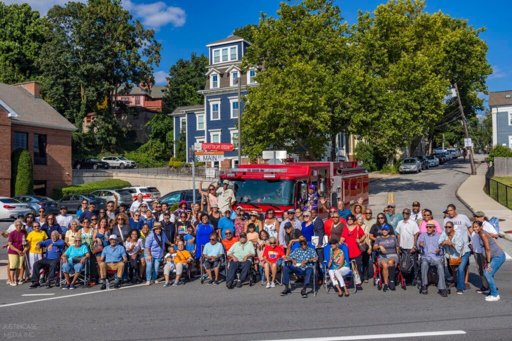 A large bunch of community members standing in the street at the renaming ceremony.